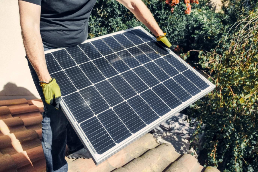 Un hombre que sostiene un panel solar para la instalación en la azotea