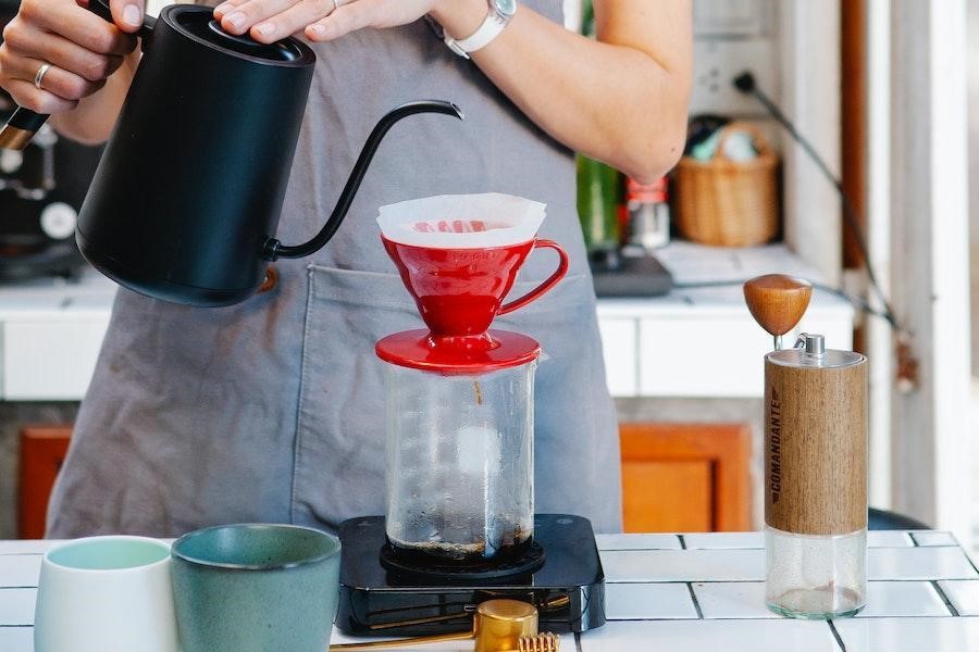 Barista vertiendo agua en una máquina de café por goteo