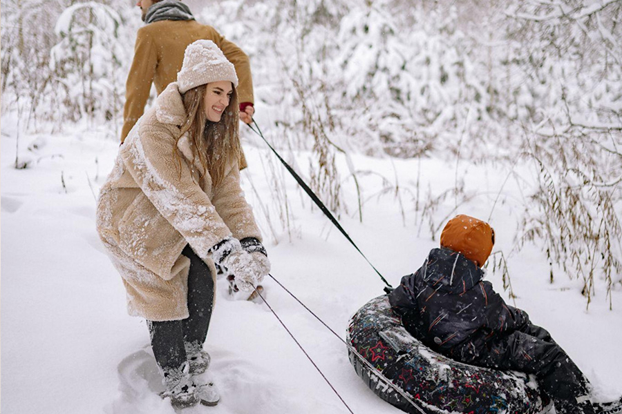 Ein Mann und eine Frau schleppen einen kleinen Jungen in einem Schlauch durch den Schnee