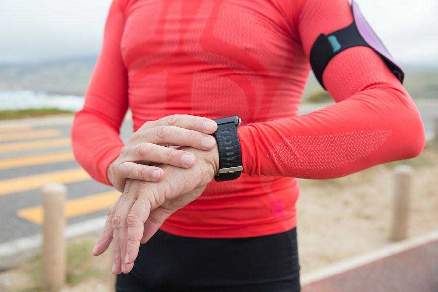 Man checking a watch while wearing a red activewear top