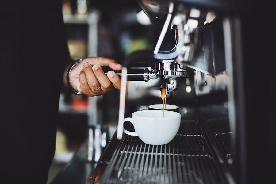 Uomo che tiene la maniglia di una macchina da caffè