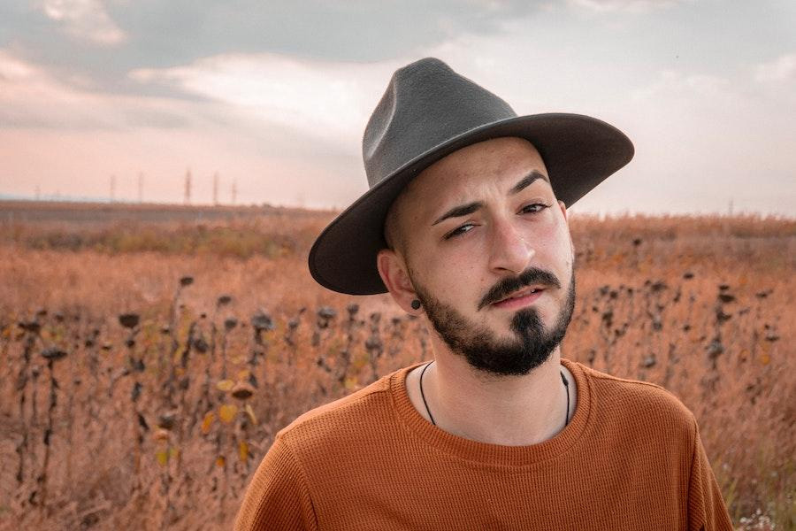 Uomo con un top arancione che indossa un cappello di feltro