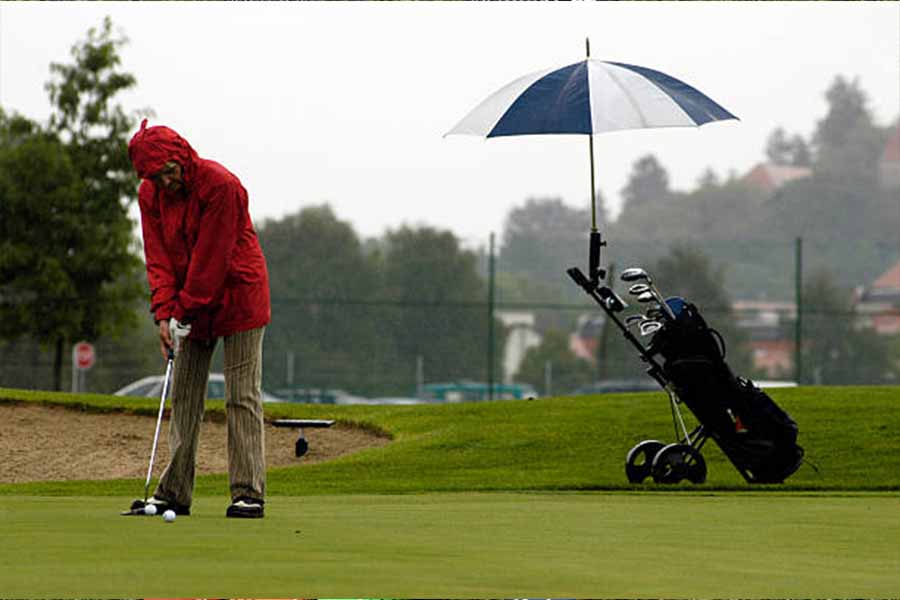 Uomo che gioca a golf sotto la pioggia con sacca da golf impermeabile