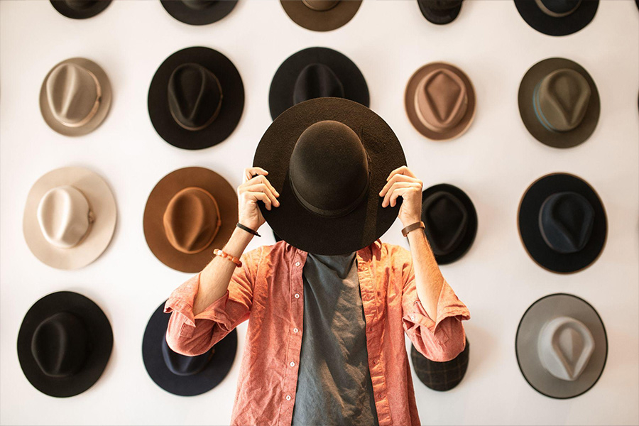 Un uomo in piedi in una stanza piena di cappelli fedora