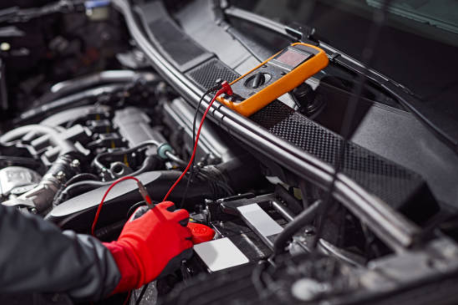 mécanicien dans des gants de protection vérifiant la tension de la batterie du véhicule