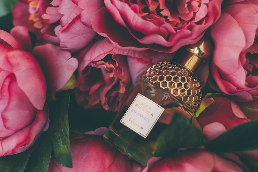 Perfume colocado entre rosas cor de rosa