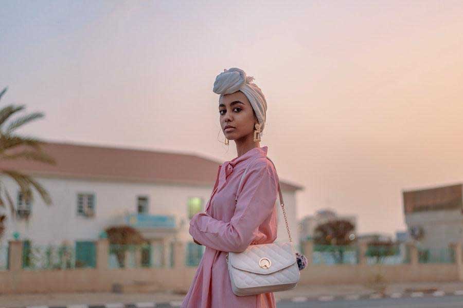 Mulher cruzando os braços enquanto balança um vestido rosa