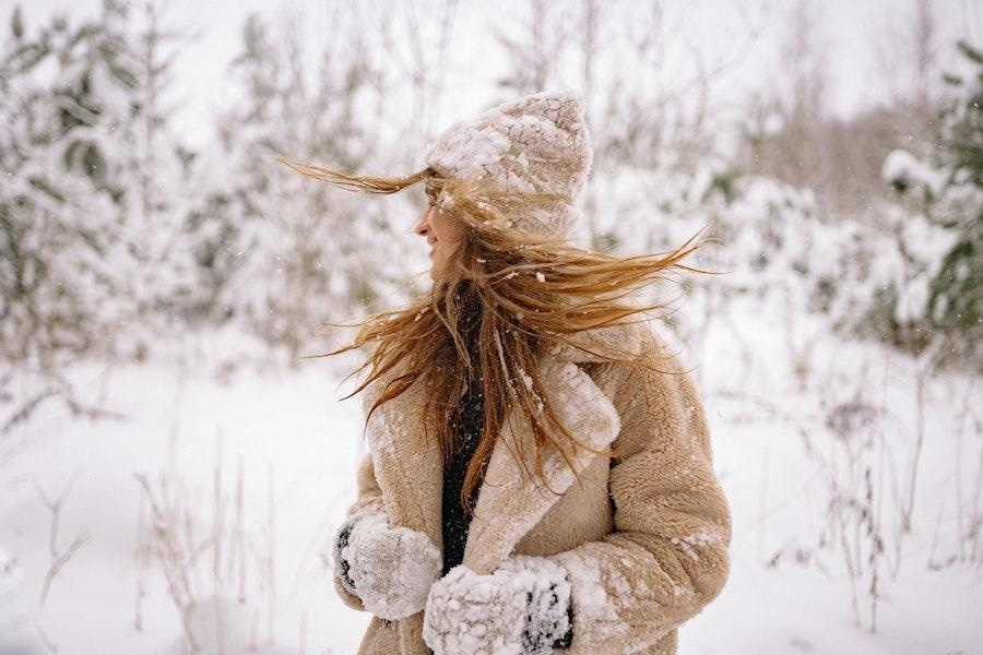 Donna nella neve che indossa un berretto di lana marrone