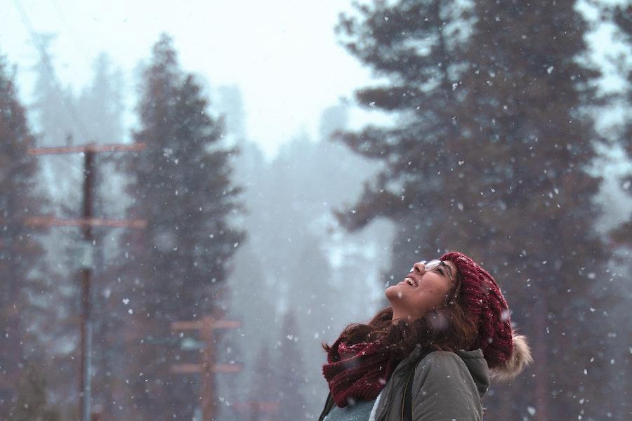 Mulher olhando para baleia usando um gorro de pom-pom vermelho