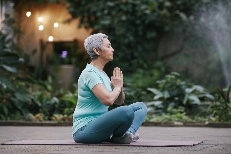 Mulher meditando em uma camisa básica azul e leggings