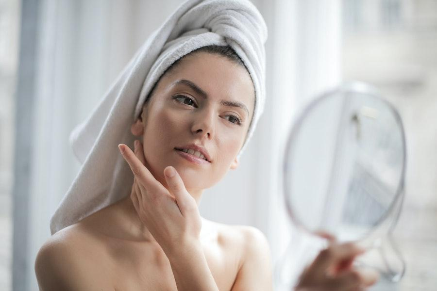 Mulher realizando rotina de beleza na frente de um espelho