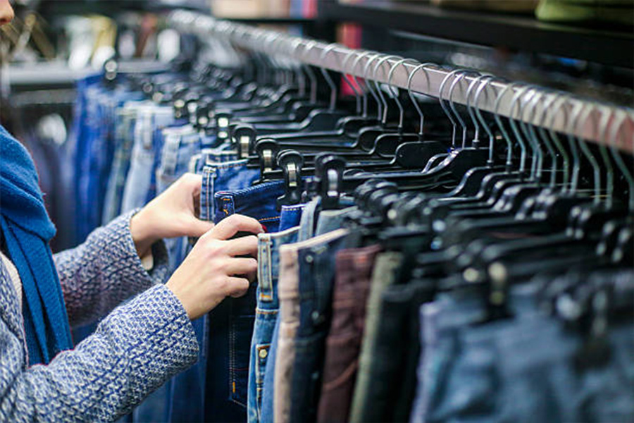 Mujer sacando jeans de un estante en una tienda