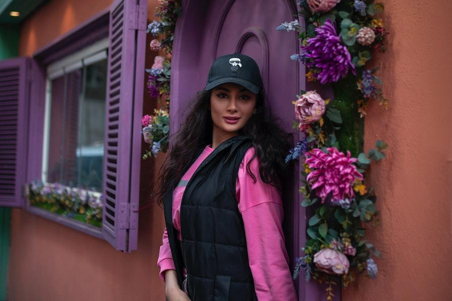 Mulher posando com um boné de beisebol preto