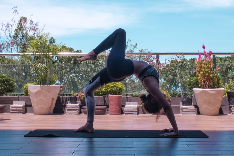 Mujer de pie y sosteniendo esterilla de yoga azul