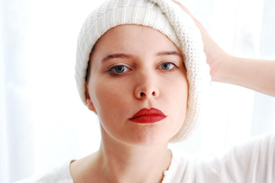 Mulher estilizando um gorro branco de lado