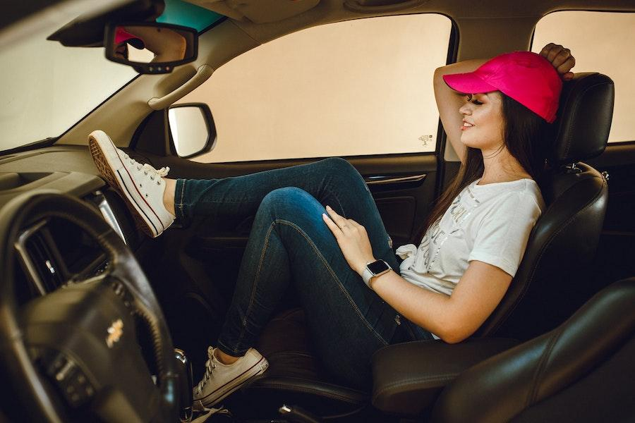 Donna che indossa un cappello da baseball rosa che si rilassa in un'auto