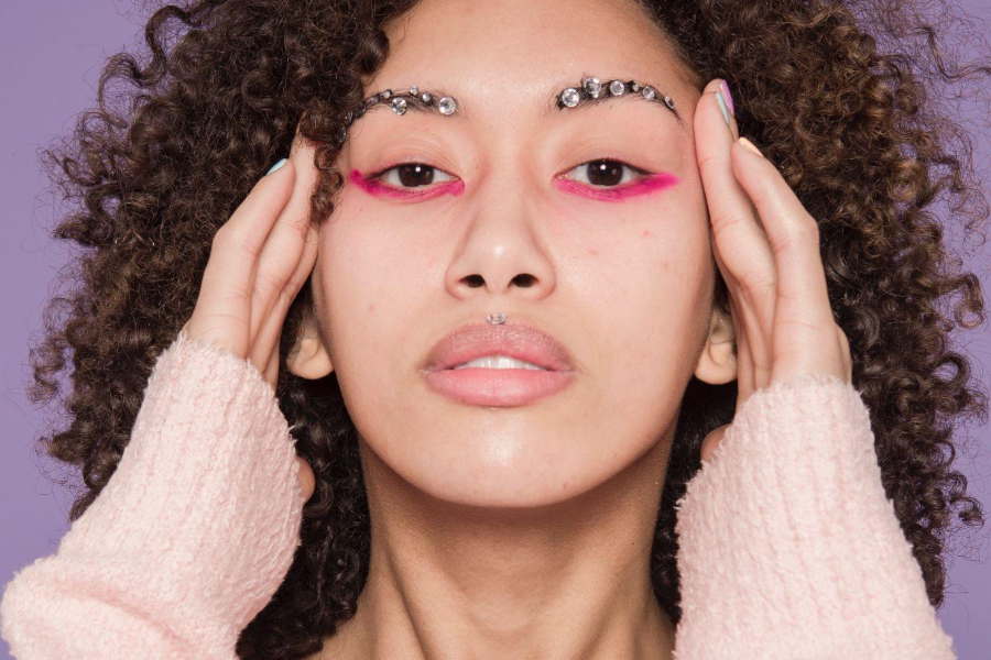 Mujer con joyas en las cejas y maquillaje de ojos rosados