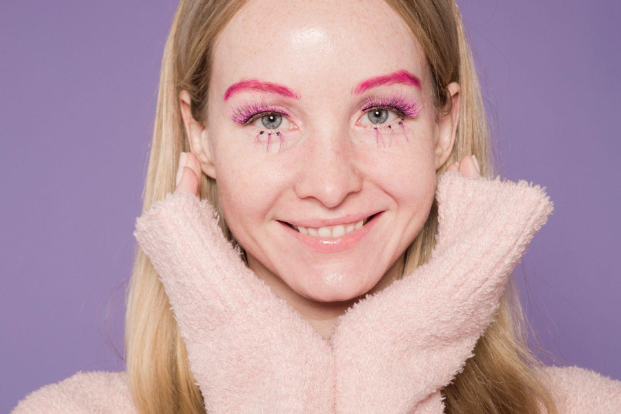 Mujer con cejas rosadas y maquillaje de ojos colorido