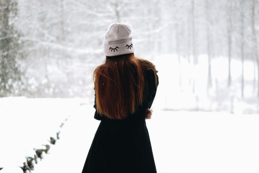 Uma mulher usando um gorro branco bordado com os olhos fechados