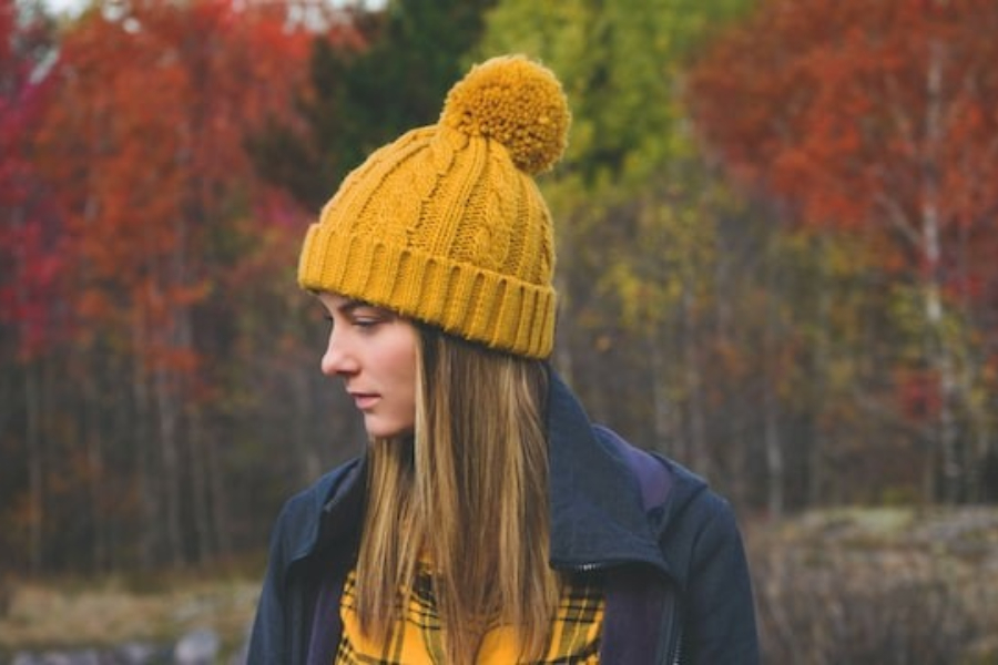 Uma mulher usando um gorro de pom-pom de tricô amarelo