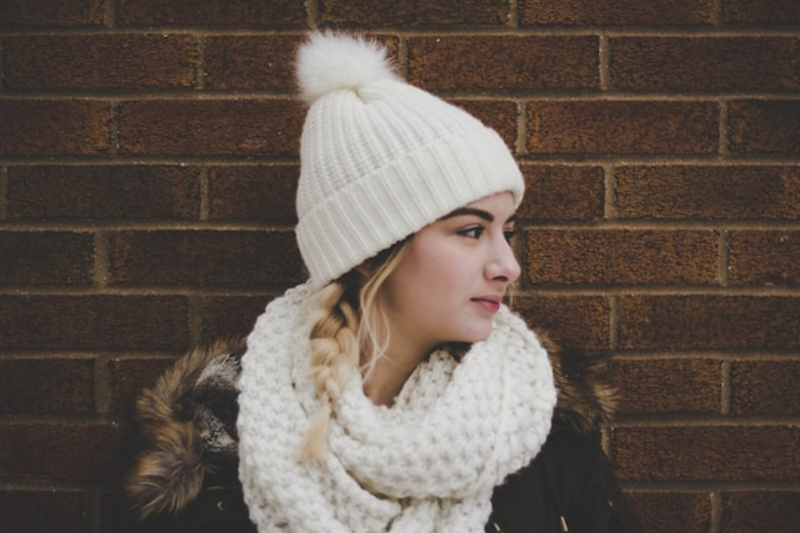 A woman wearing an ivory pom pom beanie