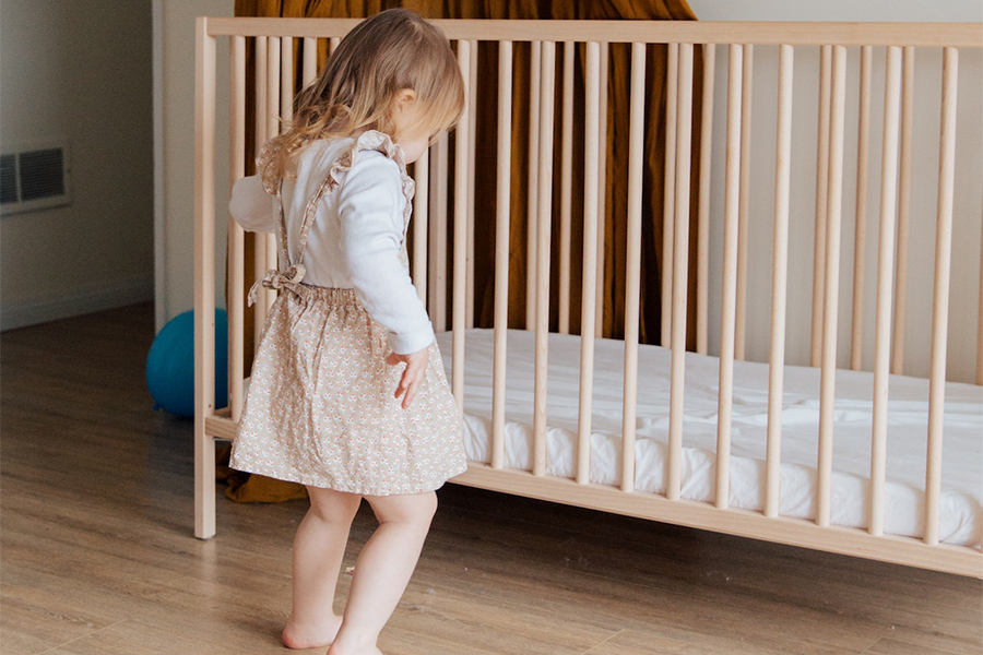 Petite fille debout à côté d'un berceau