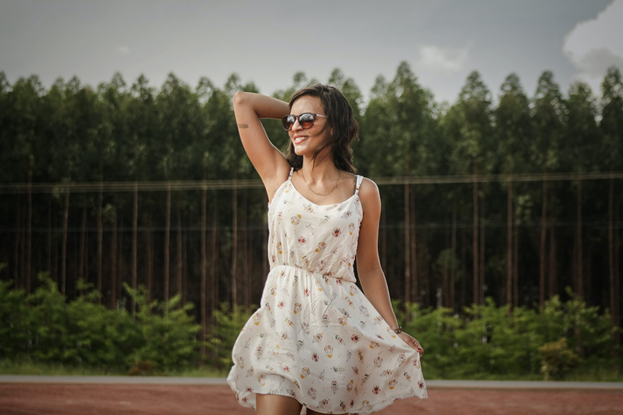 Frau trägt weißes Blumenkleid und Sonnenbrille